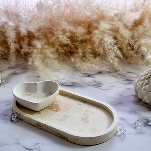 May include: A set of three white ceramic decorative boxes with geometric patterns. The boxes are arranged on a white marble surface with a fluffy white pampas grass in the background.