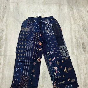 May include: Wide-leg trousers featuring a patchwork design in various shades of navy blue. The garment is constructed from multiple fabric panels, each displaying distinct floral, geometric, and paisley patterns, with an elasticized drawstring waist.