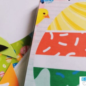 K&ouml;nnte beinhalten: Nahaufnahme eines bunten Osterei-Designs mit gelben, orangefarbenen, roten, wei&szlig;en und gr&uuml;nen Streifen und Mustern. Das Design befindet sich auf einem wei&szlig;en Hintergrund, wobei im Hintergrund liniertes Notizbuchpapier sichtbar ist.