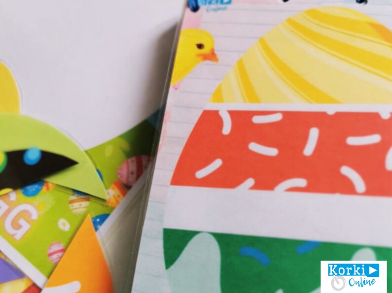 K&ouml;nnte beinhalten: Nahaufnahme eines bunten Osterei-Designs mit gelben, orangefarbenen, roten, wei&szlig;en und gr&uuml;nen Streifen und Mustern. Das Design befindet sich auf einem wei&szlig;en Hintergrund, wobei im Hintergrund liniertes Notizbuchpapier sichtbar ist.