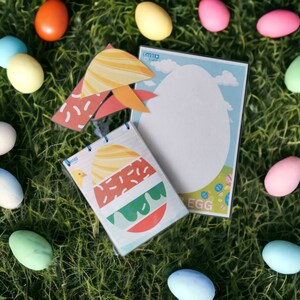 K&ouml;nnte beinhalten: Eine bunte Oster-Eier-Bastelarbeit mit einer leeren Eier-Vorlage, einer gemusterten Eier-Vorlage und einer H&uuml;hner-Illustration. Die Bastelei befindet sich auf einem gr&uuml;nen Gras-Hintergrund mit bunten Plastik-Eiern.