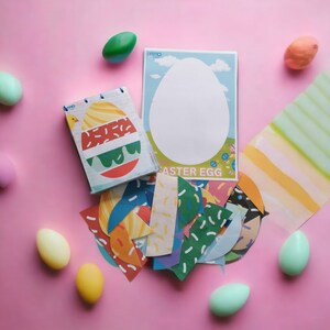 K&ouml;nnte beinhalten: Ein bunter Satz Osterei-Aufkleber mit verschiedenen Mustern und Designs. Die Aufkleber sind auf einem rosa Hintergrund mit einer leeren wei&szlig;en Osterei-Karte und ein paar Plastik-Ostereiern angeordnet.