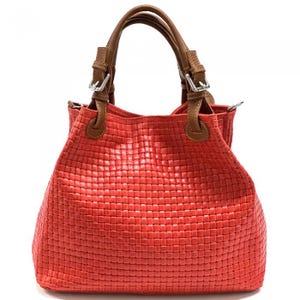 Peut inclure: Un sac à main rouge vif présentant une texture tressée sur tout le corps. Le sac comprend deux anses en cuir marron fixées par des boucles en métal argenté. Le design possède une base structurée et une large ouverture sur le dessus.