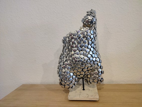 Female torso made of aluminum on a natural stone base