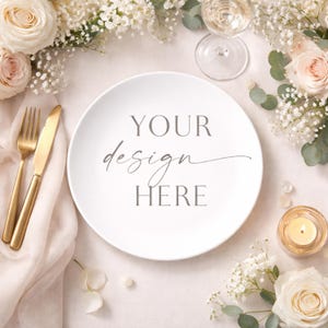 May include: A white plate with the text "YOUR design HERE" in grey script is surrounded by flowers, a gold fork and knife, a glass of champagne, and a lit candle. The scene is set on a light pink surface, creating an elegant, romantic aesthetic.