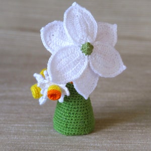 May include: A crocheted flower arrangement in a green vase. The flowers are white with yellow centers.