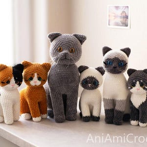 May include: A collection of six crocheted cat plushies in various colors and patterns, including calico, orange, grey, and Siamese styles, all featuring large plastic eyes and stitched details, with the text AniAmiCrochet visible at the bottom.