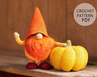 Puede incluir: Patrón de crochet PDF para un gnomo sosteniendo una calabaza amarilla. El gnomo lleva un gorro naranja y tiene una barba roja.