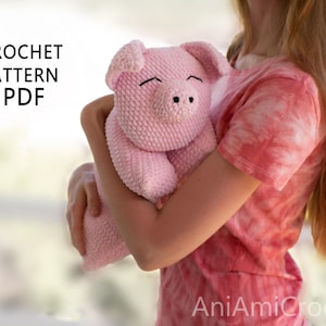K&ouml;nnte beinhalten: Ein geh&auml;keltes rosa Schwein-Stofftier mit strukturierter Garnoberfl&auml;che, Schlappohren und einer Schnauze mit zwei schwarzen Nasenl&ouml;chern. Der Text CROCHET PATTERN PDF ist oben links und AniAmiCrochet unten rechts zu sehen.