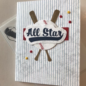 May include: A white card with blue and red stripes. A baseball with crossed bats and the text "All Star" is on the card.