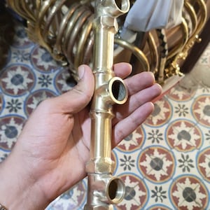 以下が含まれることがあります： 3つのアウトレットが付いた真鍮製の配管継手。継手は竹の様にデザインされています。