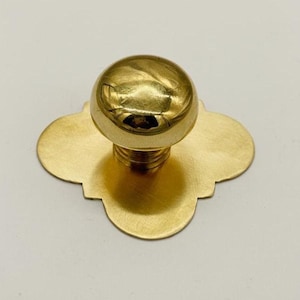 以下が含まれることがあります： 丸い上部と四つ葉のクローバー型のベースを備えた、金色のキャビネットノブ。ノブには、取り付けを容易にするためのねじ付きポストが付いています。このハードウェアは真鍮製で、引き出し、キャビネット、家具に適しています。