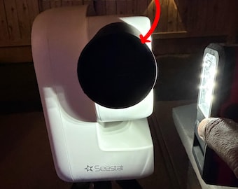 Puede incluir: Un telescopio Seestar S50 blanco con un protector de luz cilíndrico negro acoplado a la lente frontal. El texto S50 PRO LIGHT SHIELD y NO LIGHT LEAK es visible sobre el dispositivo, con una flecha roja señalando el protector.