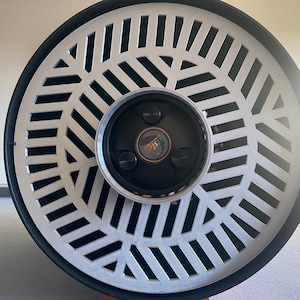 May include: A close-up of a white and black circular speaker with a silver grill and a black center with the word "DISCO" in rainbow letters.