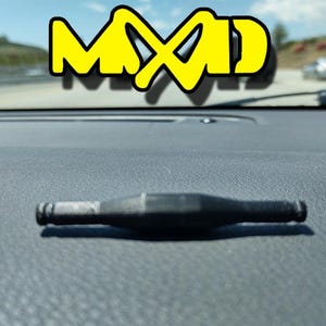 May include: A black rubber car part with a textured surface. The part has two ends with a small hole in each end.