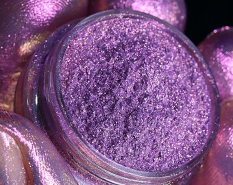 May include: A small jar of purple glitter with a clear lid. The glitter is very fine and has a slight iridescent sheen.