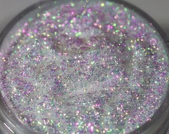 May include: A small clear jar filled with iridescent glitter. The glitter is a mix of white, pink, and green.