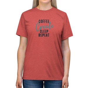 May include: A red heather t-shirt with the text "COFFEE Create SLEEP REPEAT" in black and teal lettering.