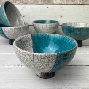 May include: Set of five small ceramic bowls with a crackled glaze finish. The bowls are in shades of blue and white and have a unique, rustic look.