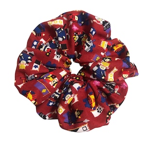May include: Red scrunchie with a repeating pattern of small, colorful Japanese characters and flags.
