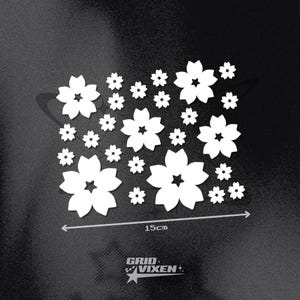 Könnte beinhalten: Weiße, blütenförmige Aufkleber in verschiedenen Größen auf schwarzem Hintergrund. Die größten Blüten messen 15 cm. Das Grid Vixen-Logo befindet sich unten. Geeignet für dekorative Zwecke.