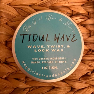 May include: A round, teal-colored container of "TIDUL WAVE" hair wax, with text indicating it's for waves, twists, and locks. The label also states it contains organic ingredients, including mango, avocado, and vitamin E. The container is 4 oz. or 120ml.