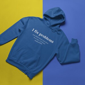 May include: A blue hooded sweatshirt with the text "I fix problems you didn't know you have in a way, you don't understand." printed on the front.