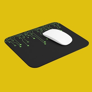 May include: A black mouse pad with a green circuit board design and a white wireless mouse on top.