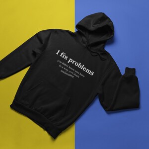 May include: Black hooded sweatshirt with the text "I fix problems you didn't know you have in a way, you don't understand." printed in white on the front.