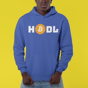 Puede incluir: Una sudadera con capucha azul con la palabra "HODL" en letras blancas. La "O" se reemplaza con un símbolo de Bitcoin dentro de un círculo naranja. La sudadera tiene un bolsillo delantero y una capucha.