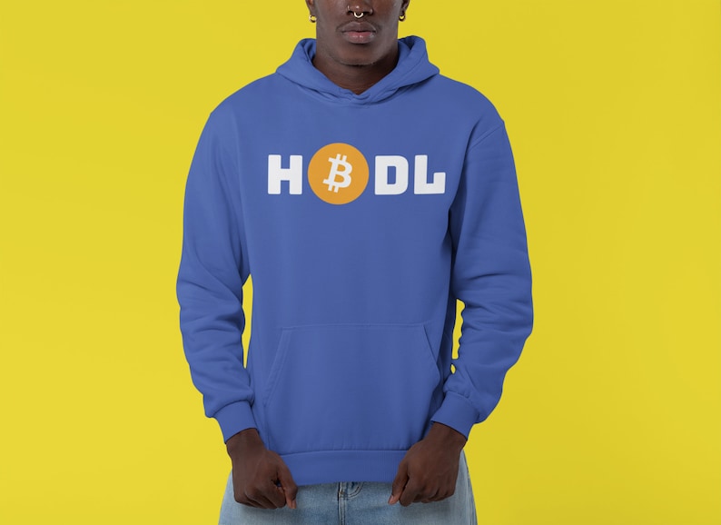 以下が含まれることがあります： 白い文字で「HODL」という言葉が入った青いパーカー。 「O」はオレンジ色の円の中のビットコインのシンボルに置き換えられています。 パーカーにはフロントポケットとフードが付いています。