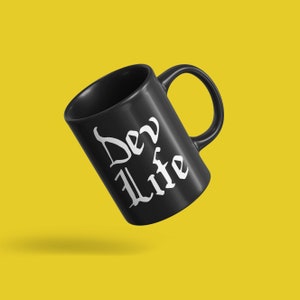 Könnte beinhalten: Schwarze Keramiktasse mit einer weißen Aufschrift "Dev Life".