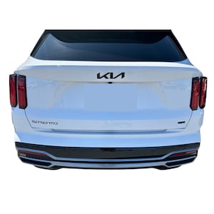 May include: Rear view of a white Kia Sorento SUV. The vehicle has black accents, including the bumper and the Kia logo. The taillights are red. The word "Sorento" is displayed in black lettering.