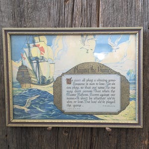 May include: A framed print featuring a sailing ship on blue water with seagulls in a pale sky. A central decorative plaque contains the text: Playing the Game. We can't all play a winning game. Someone is sure to lose. Yet we can play, so that our name. No one may dare accuse. That when the Master Referee. Scores against our name. It won't be whether we've won or lost. But how we've played the game. D.M. Downie.