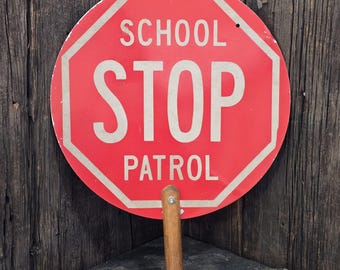 Señal de tráfico vintage de patrulla escolar con forma de piruleta y mango de madera.