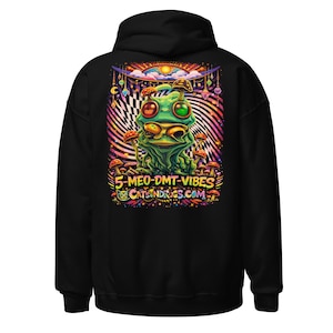 Puede incluir: Sudadera con capucha negra con un diseño gráfico colorido de una rana verde con detalles de hongos. El diseño incluye el texto "5-MEO-DMT-VIBES" y "CATSNDRUGS.COM" en un estilo psicodélico, sobre un fondo vibrante.