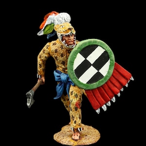 Op de afbeelding: Een handgeschilderd beeldje van een Azteekse krijger met een jaguar masker en een verenhoed, die een schild en een bijl vasthoudt. De krijger is gedetailleerd en realistisch geschilderd, met een verscheidenheid aan kleuren en texturen.