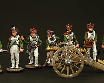 May include: A set of seven hand-painted miniature figures depicting soldiers and a cannon. The figures are dressed in green and white uniforms with red accents. The cannon is made of metal and wood and has a black barrel. The figures are posed in a variety of stances, some holding muskets and others holding swords.