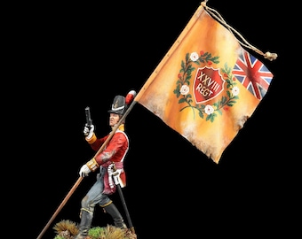 May include: A hand-painted miniature soldier figure in a red uniform holding a tall pole with a large yellow flag. The flag features a red shield with the text XXVIII REGT, a green wreath, white roses, and a small Union Jack in the corner.