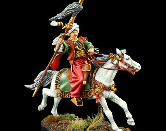 May include: A hand-painted miniature figure of a mounted soldier wearing a red and green uniform, holding a spear with a black and white plume. The soldier is riding a white horse with a saddle and bridle decorated with gold and red accents.