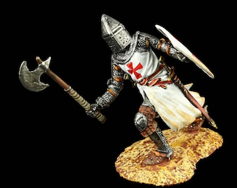 Puede incluir: Figura detallada de un caballero medieval con armadura plateada, sosteniendo un hacha de batalla y un escudo. El caballero lleva una túnica blanca con una cruz roja, un casco y cota de malla. La figura está sobre una base texturizada y marrón.