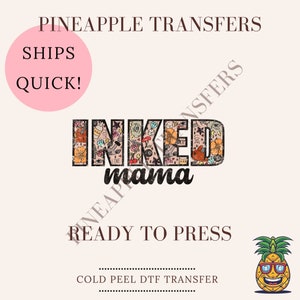 May include: A ready-to-press iron-on transfer featuring the text "INKED mama" in black with a colorful tattoo-style design. The transfer is a cold peel DTF transfer.