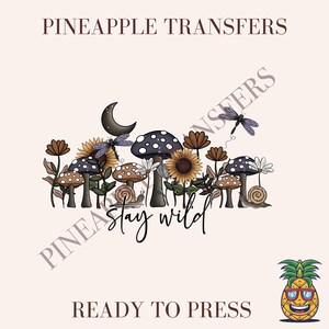 May include: A ready-to-press iron-on transfer design featuring a whimsical illustration of mushrooms, sunflowers, and a dragonfly with the text "Stay Wild".