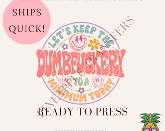 May include: A pink and purple circle with the text "Let's Keep the Dumbfuckery to a Minimum Today" in a retro font. The circle is surrounded by flowers and smiley faces. The text "Ships Quick!" is in a pink circle at the top left of the image. The text "Ready to Press" is below the circle. The text "Cold Peel DTF Transfer" is below the text "Ready to Press". A cartoon pineapple with sunglasses is in the bottom right corner of the image.