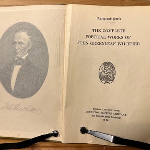 May include: A book titled "The Complete Poetical Works of John Greenleaf Whittier" published by Houghton Mifflin Company in 1910. The book cover features a black and white portrait of the author and a decorative seal.