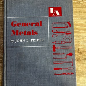 Puede incluir: Un libro azul con el título "General Metals" de John L. Feirer. El libro forma parte de la serie McGraw-Hill Publications in Industrial Arts. La portada presenta un logotipo "IA" rojo e ilustraciones de diversas herramientas de trabajo de metales.