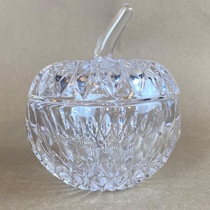 May include: A clear glass candy dish shaped like an apple with a diamond pattern. The lid has a stem.