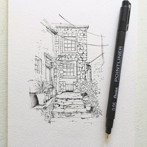 May include: A black and white pen and ink sketch of a stone building with a doorway and steps, with potted plants on either side. A black Pentel Pointliner pen is positioned to the right of the drawing.