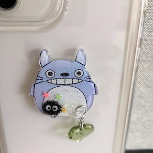 May include: A blue and white Totoro character phone charm with a small black soot sprite character and green leaves.