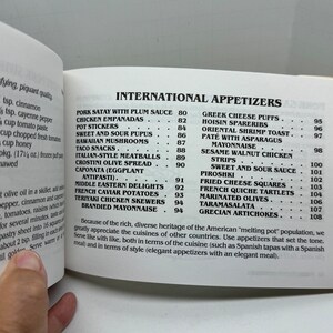 May include: A page from a cookbook featuring a list of international appetizers with their corresponding page numbers. The appetizers include Pork Satay with Plum Sauce, Chicken Empanadas, Pot Stickers, Sweet and Sour Pupus, Hawaiian Mushrooms, Taco Snacks, Italian-Style Meatballs, Crostini Olive Spread, Caponata (Eggplant Antipasti), Middle Eastern Delights, French Caviar Potatoes, Teriyaki Chicken Skewers, and Brandied Mayonnaise.